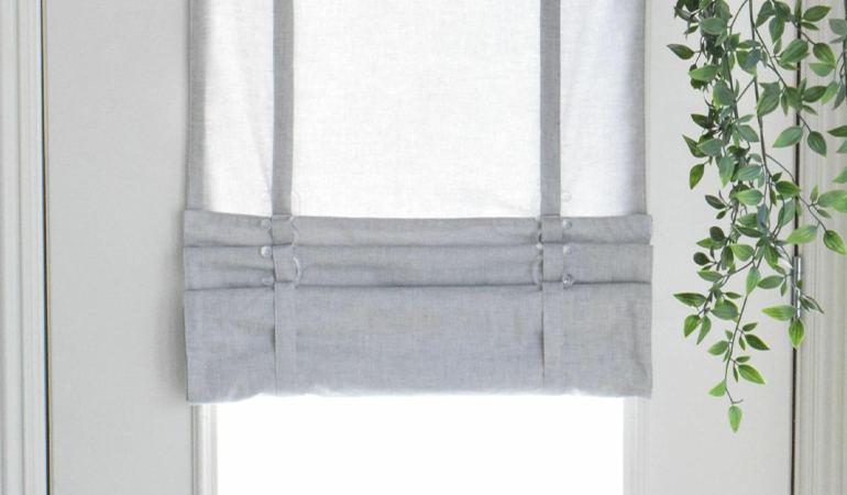 With a tiered tumble shade in San Antonio, you can block sun glare all year round. Gray rolled tumble shade on a glass door